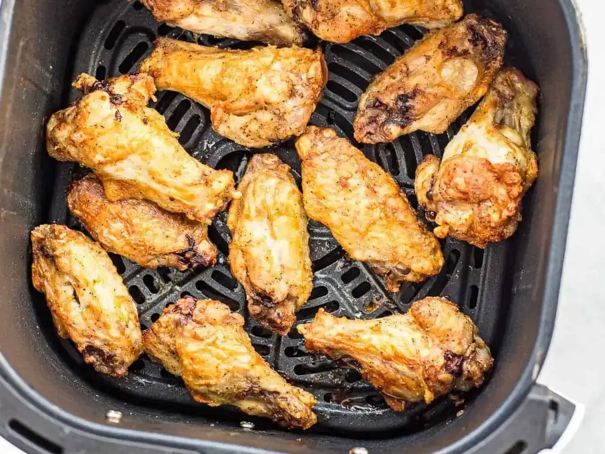 air fryer with crispy chicken wings and vegetables