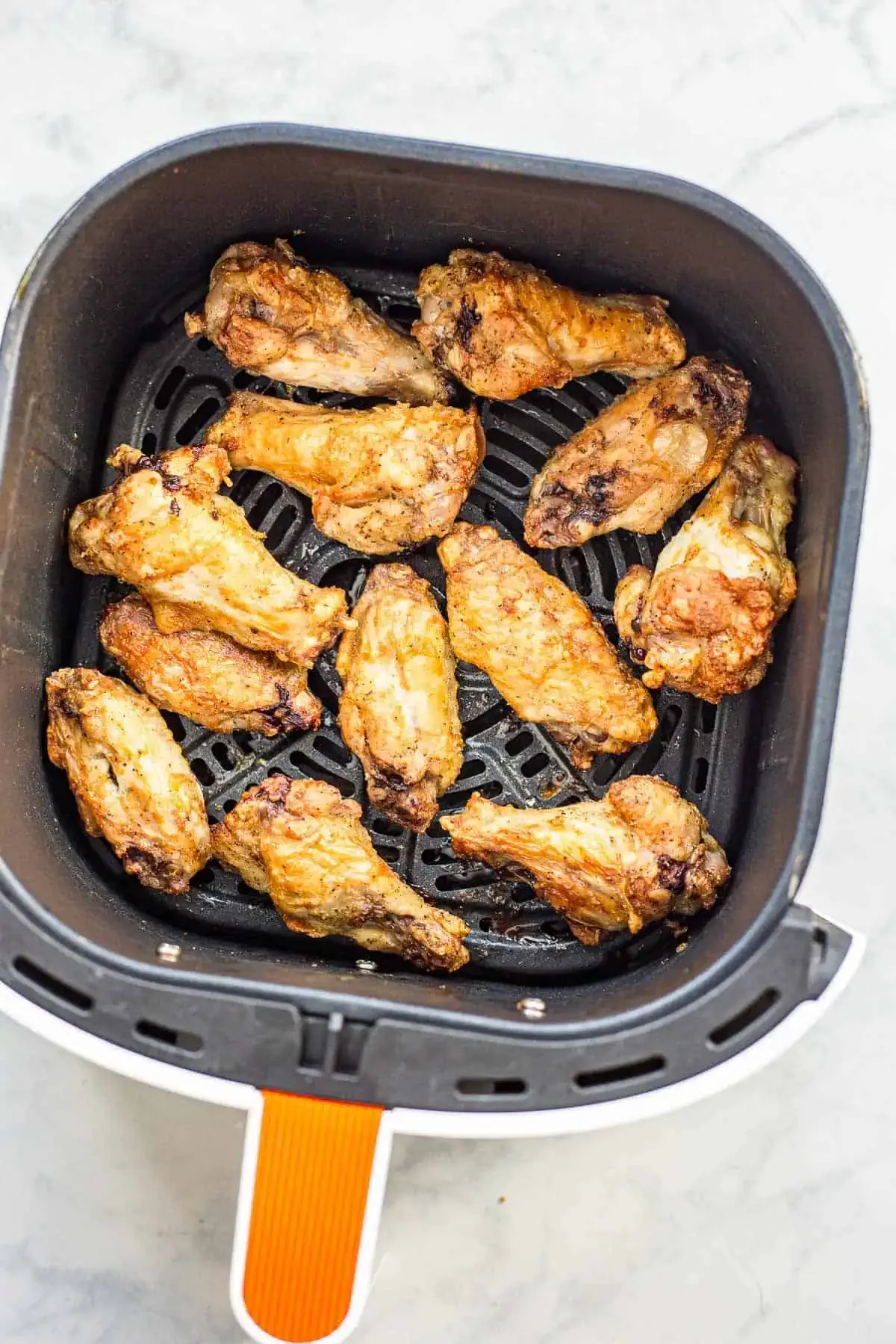air fryer with crispy chicken wings and vegetables